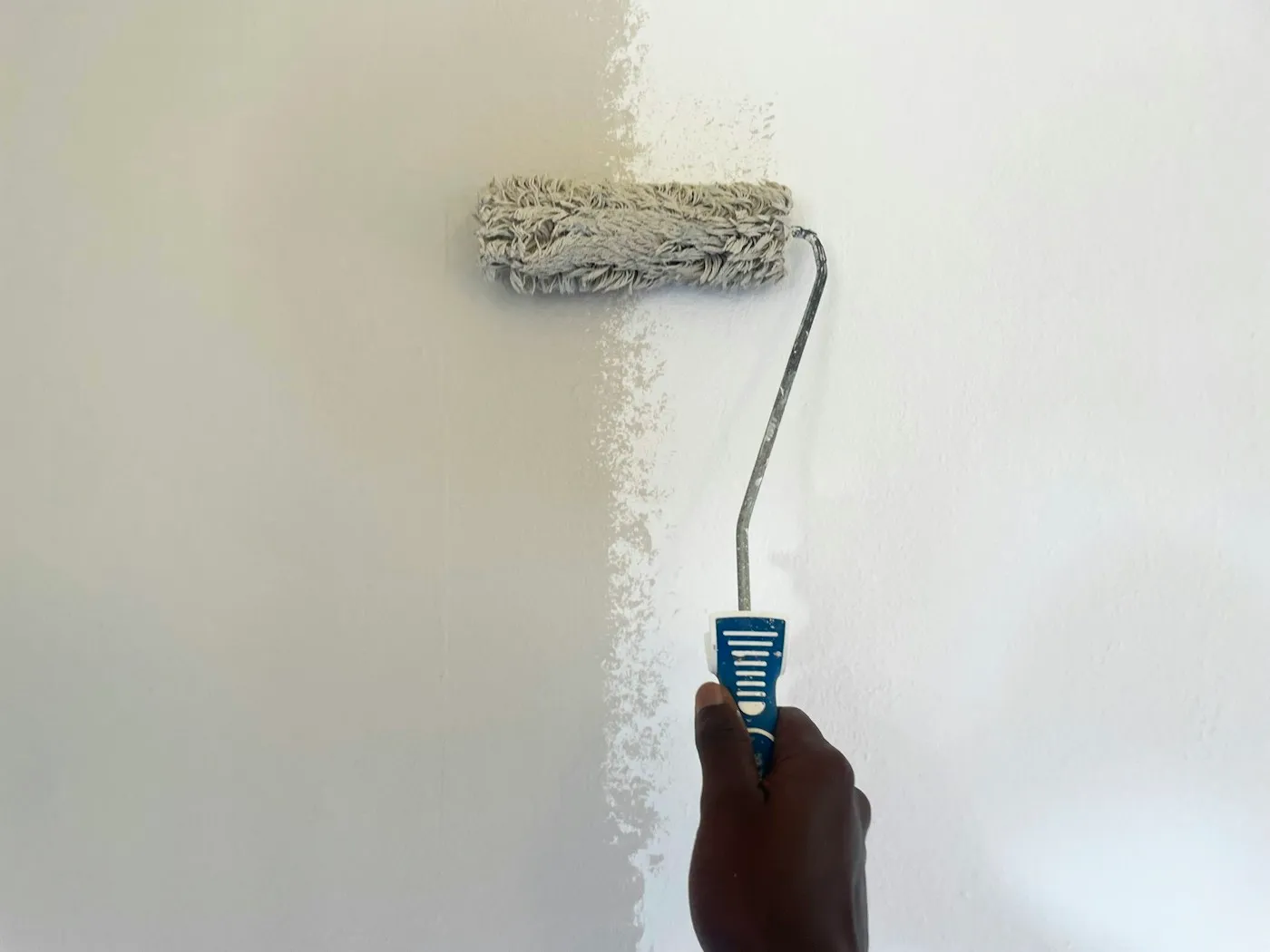 Nahaufnahme einer Farbrolle beim ersten Anstrich einer weißen Wand