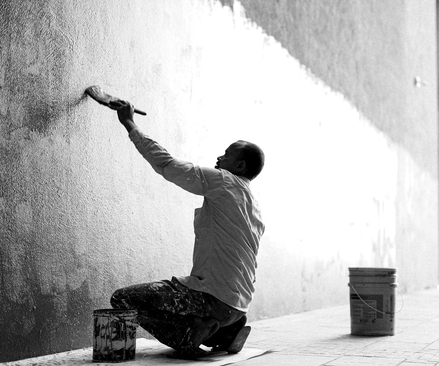 Maler streicht eine Außenfassade mit einem breiten Pinsel